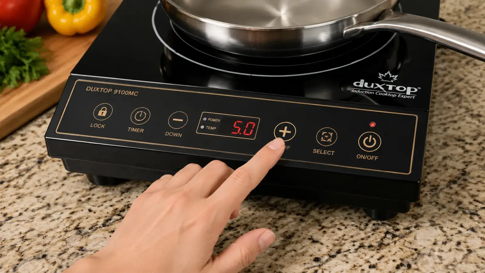 Hand pressing a power level button on the Duxtop 1800W induction cooktop sensor touch panel