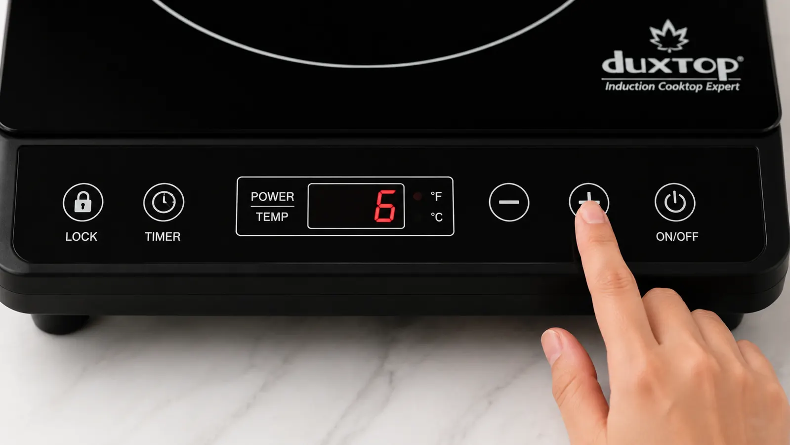 Hand adjusting the power level dial on the Duxtop 9100MC induction cooktop