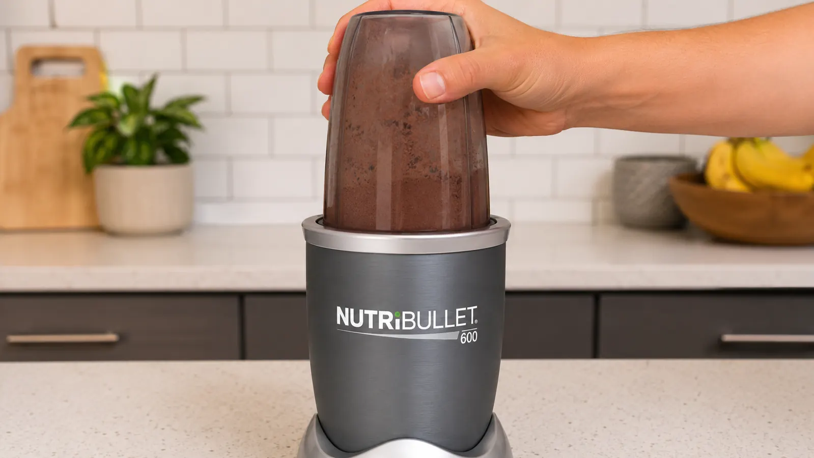 Hand pressing NutriBullet 600 cup down onto the base to blend a protein shake